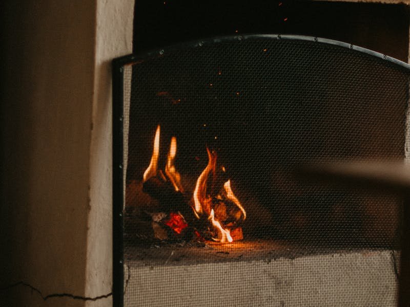 Traditional stone fireplace with mesh screen and burning logs